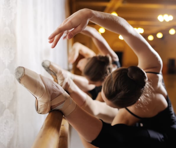three young cute ballerinas perform exercises on a choreographic machine or barre